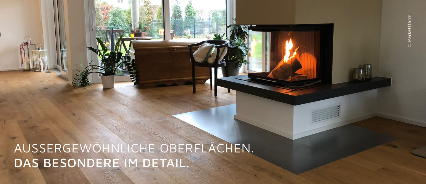 Wohnzimmer mit hervorgehobenem Parkettboden und Kamin, Text: 'Außergewöhnliche Oberflächen. Das Besondere im Detail.'