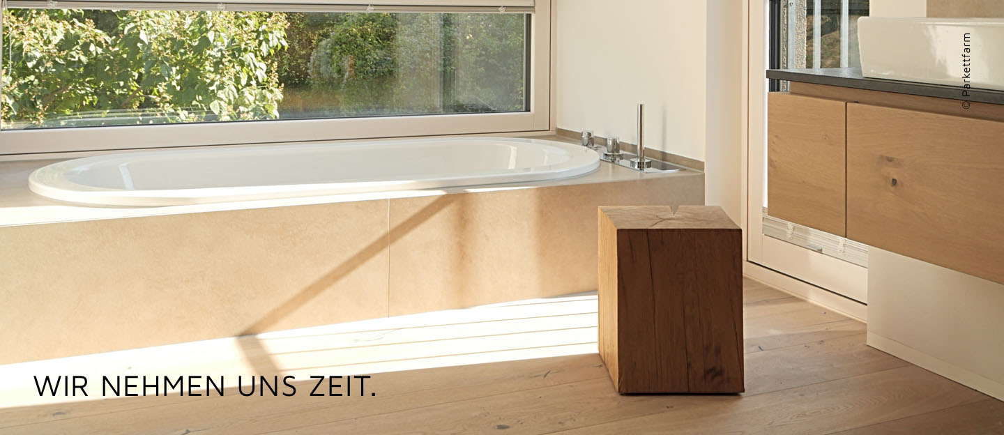 Helles Badezimmer mit großem Fenster, Badewanne und Parkettboden, Text: 'Wir nehmen uns Zeit.'